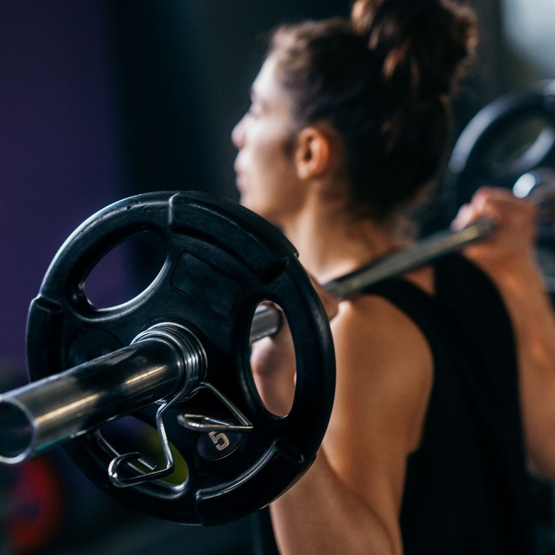 Woman lifting light weights at home to support PMOS and insulin resistance.
